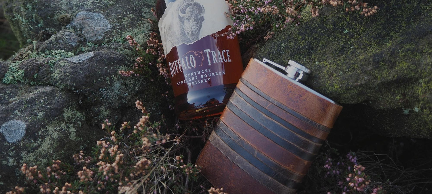 Our rust layers hip flask next to a bottle of whiskey on the moors.