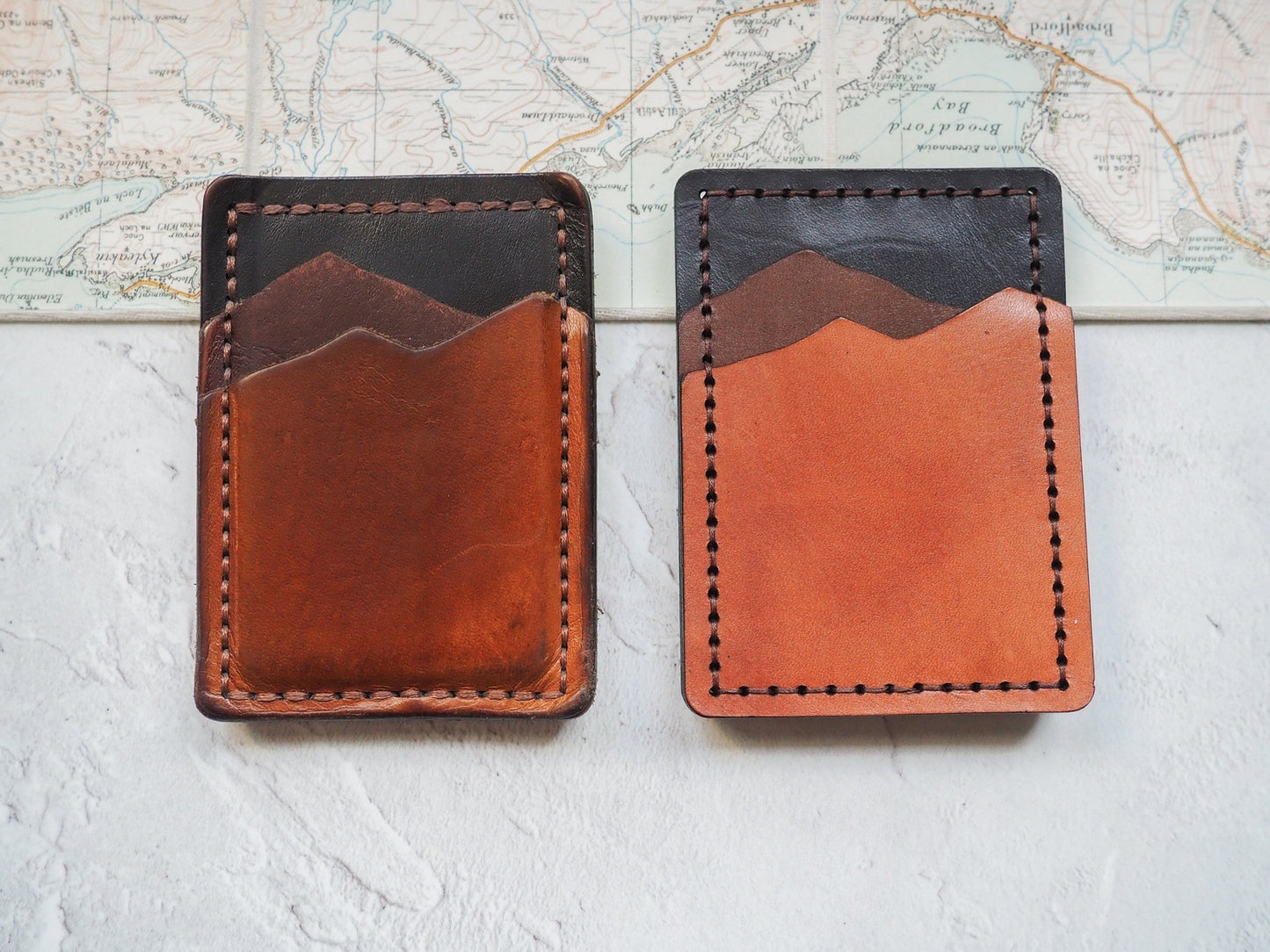 A fiver year old money clip card holder next to a brand new one, the old one shows the patina in the leather.
