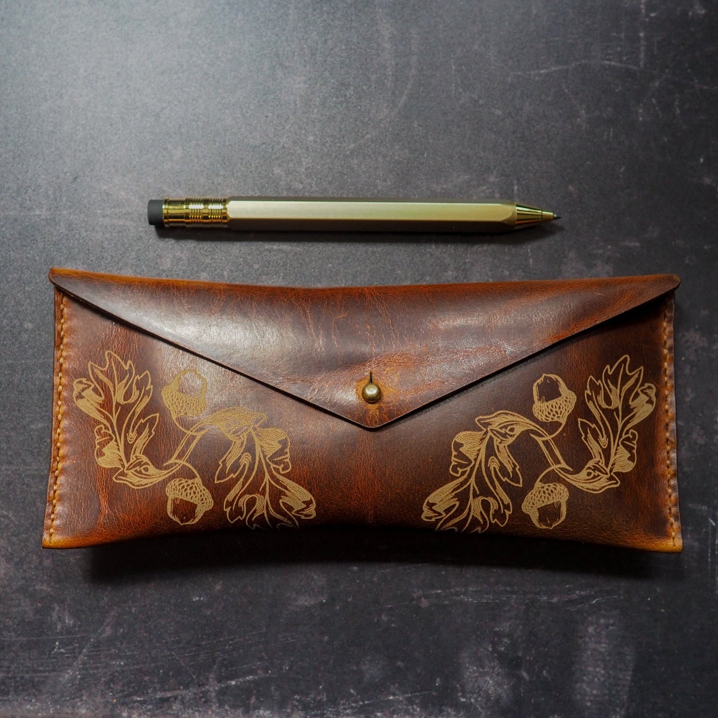 Brown leather pouch with floral embossing on a dark surface