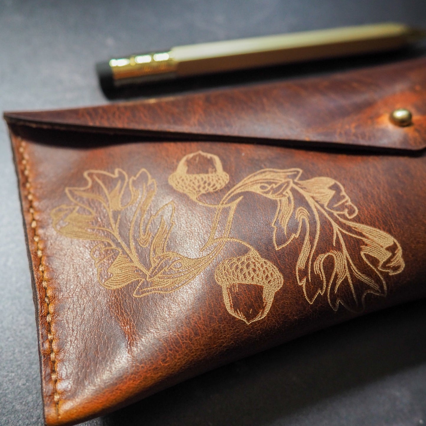 Brown leather pouch with floral embossing on a dark surface