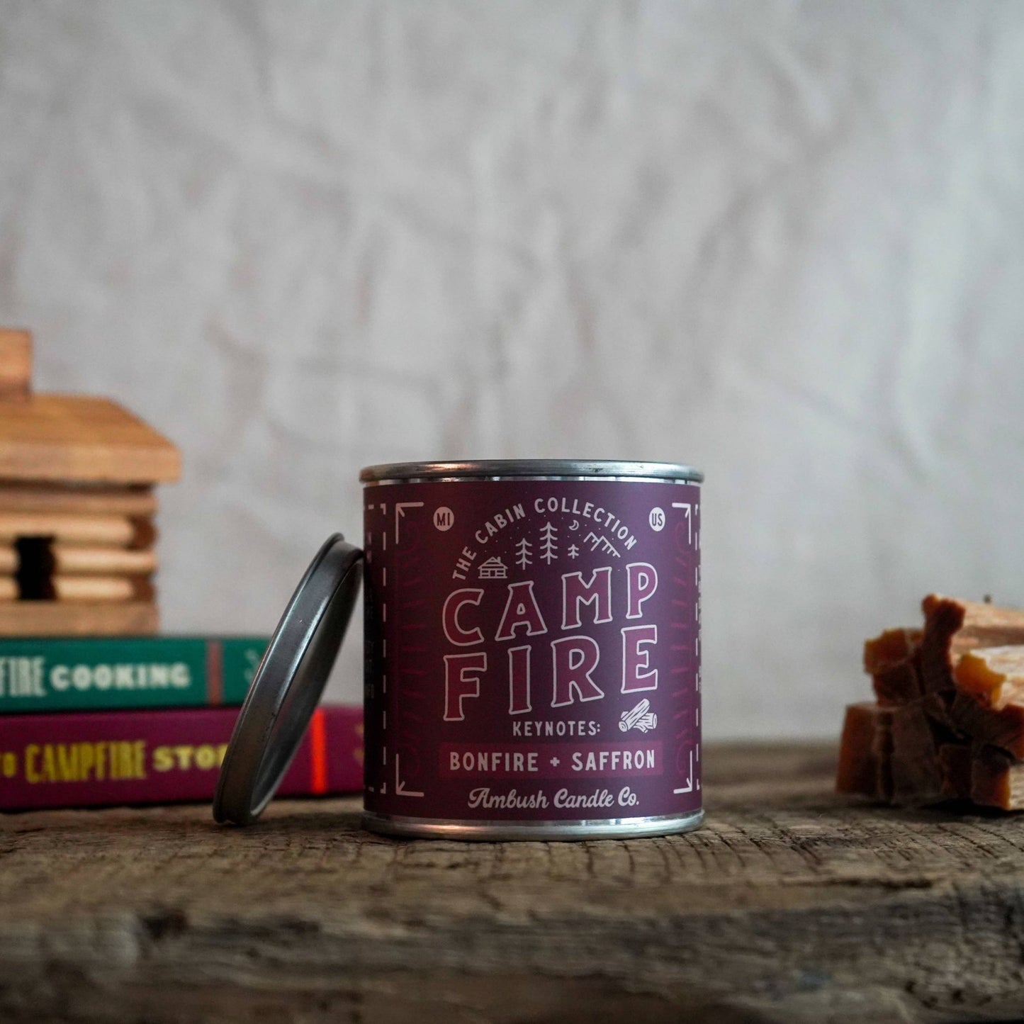 A burgundy candle in a outdoorsy pain tin, this candle has a scent profile that's inspired by Camp fires.