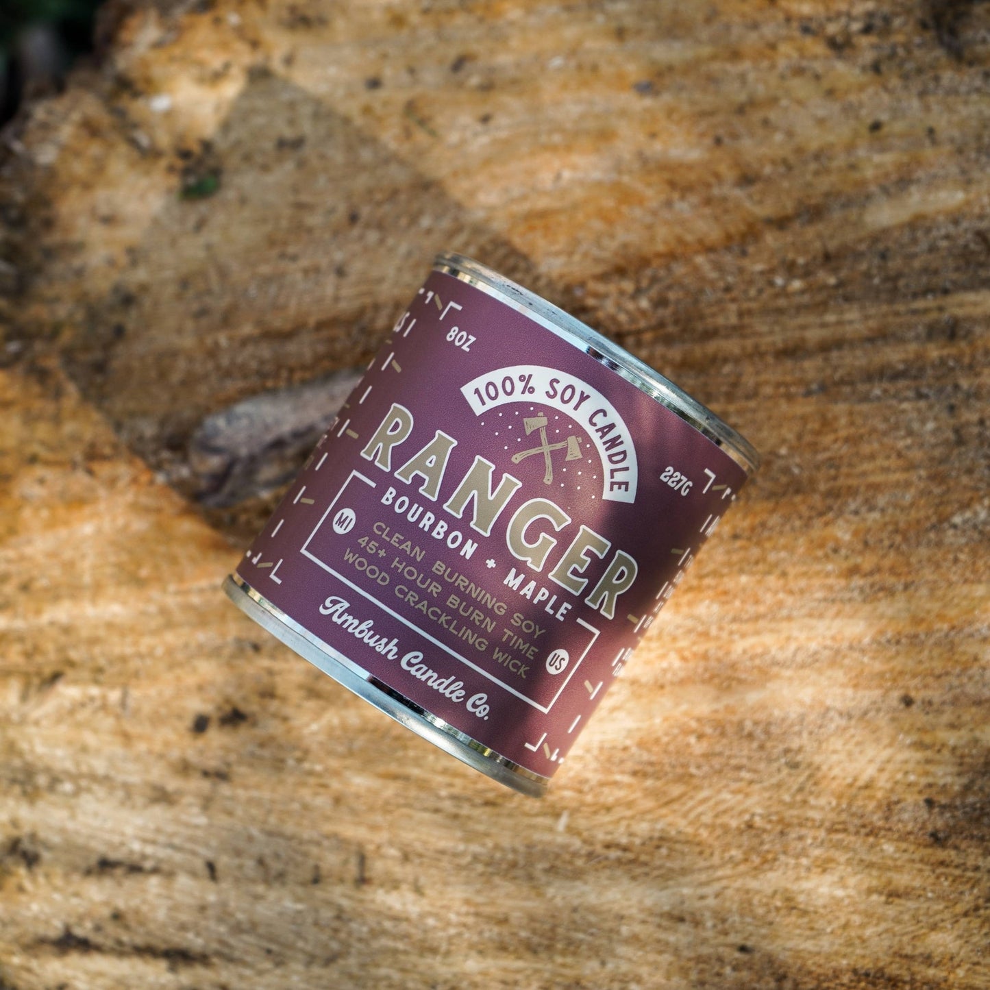 A can of Ranger bourbon + maple soy candle placed on a wooden surface with natural surroundings.
