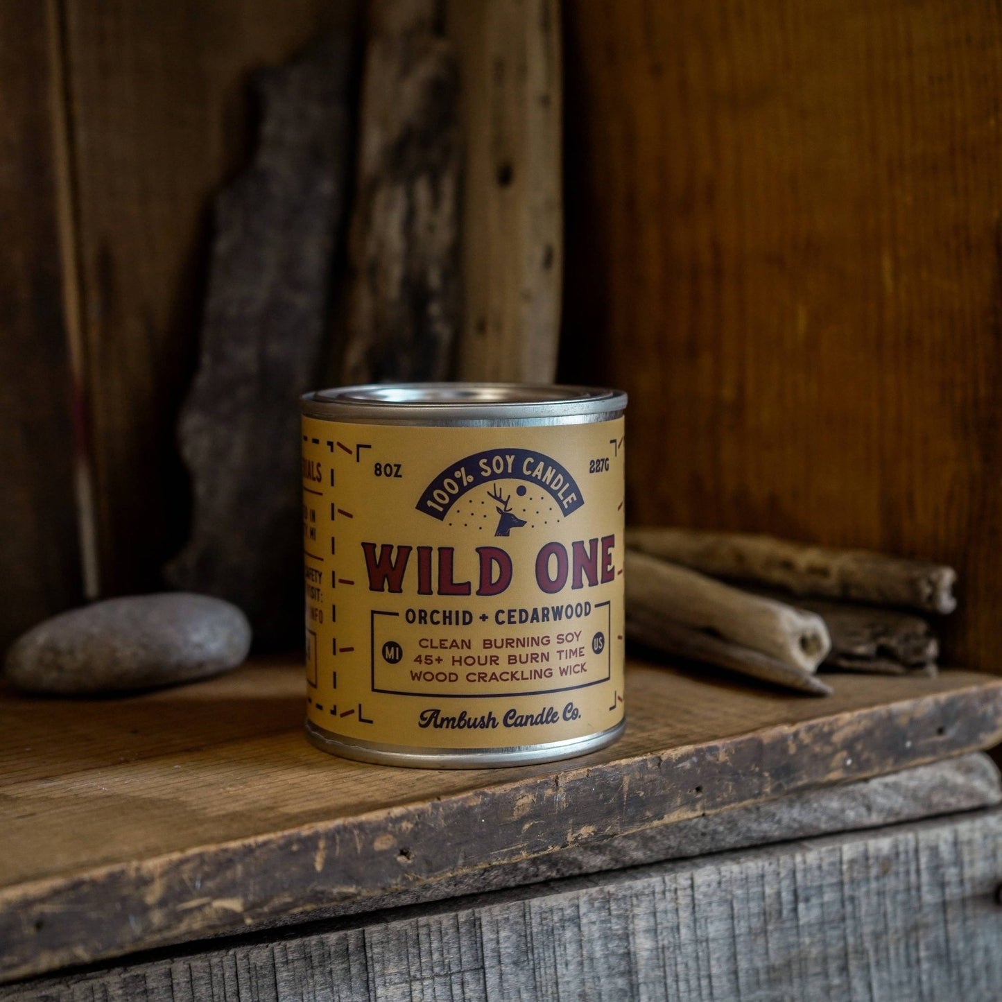 A can of 'Wild One' soy candle by Ambush Candle Co. placed on a wooden surface with a rustic background.
