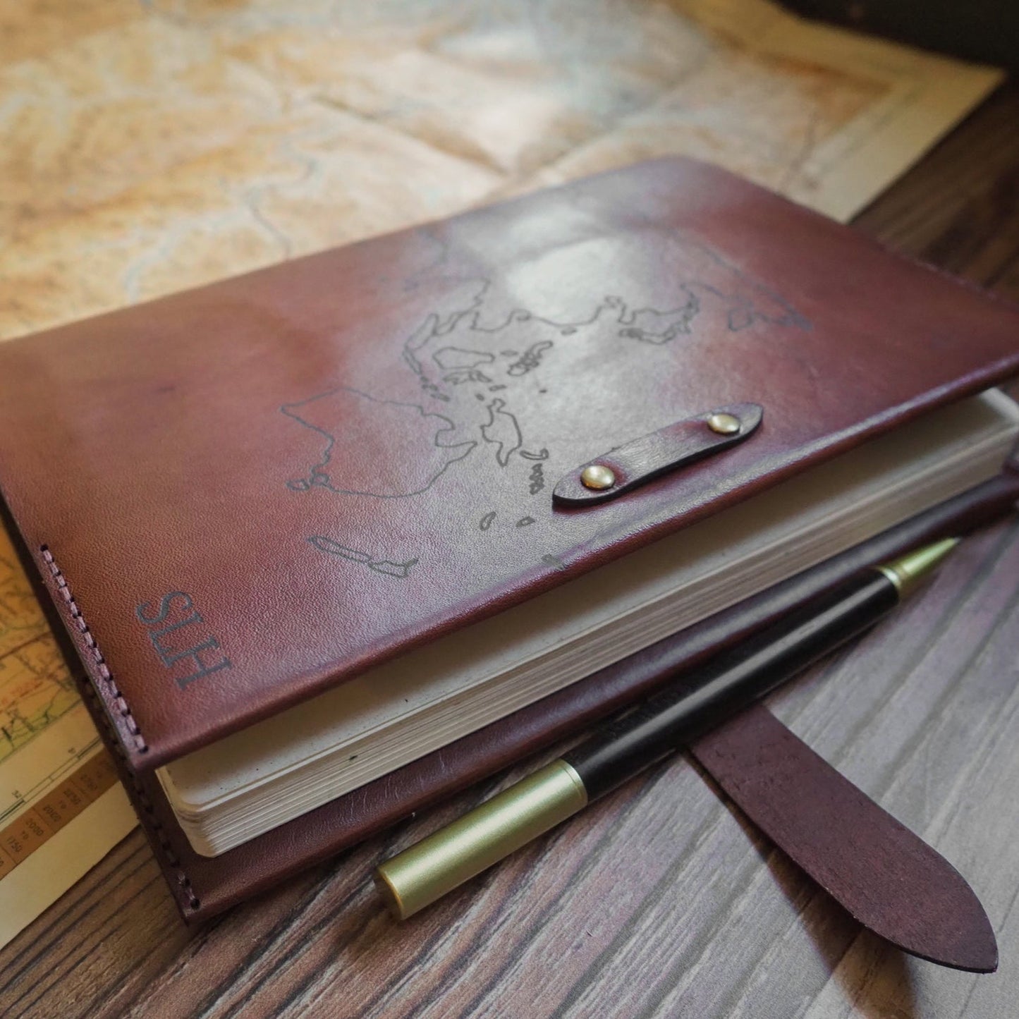 Brown leather notebook with clasp engraved  with  a world map design and monogram