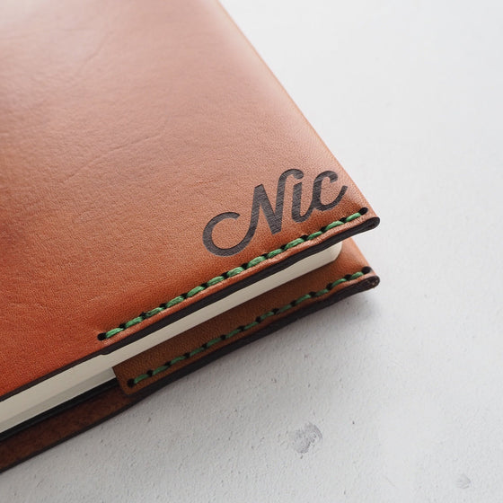 Monogrammed leather notebook cover handstitched with green double-waxed linen thread and personalised with an initial of NIC.