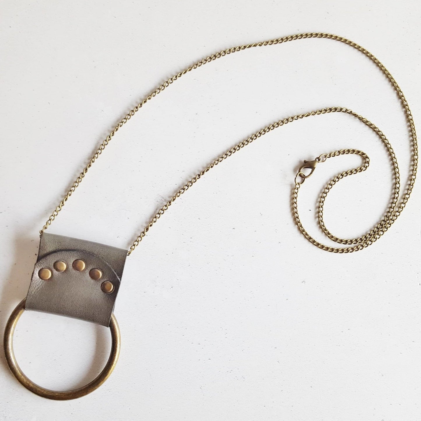 The antique green Lunar Necklace is inspired by the phases of the moon, hand dyed leather is riveted around a solid antique brass ring, on antique brass chain. a lunar moon jewelry from Hord.