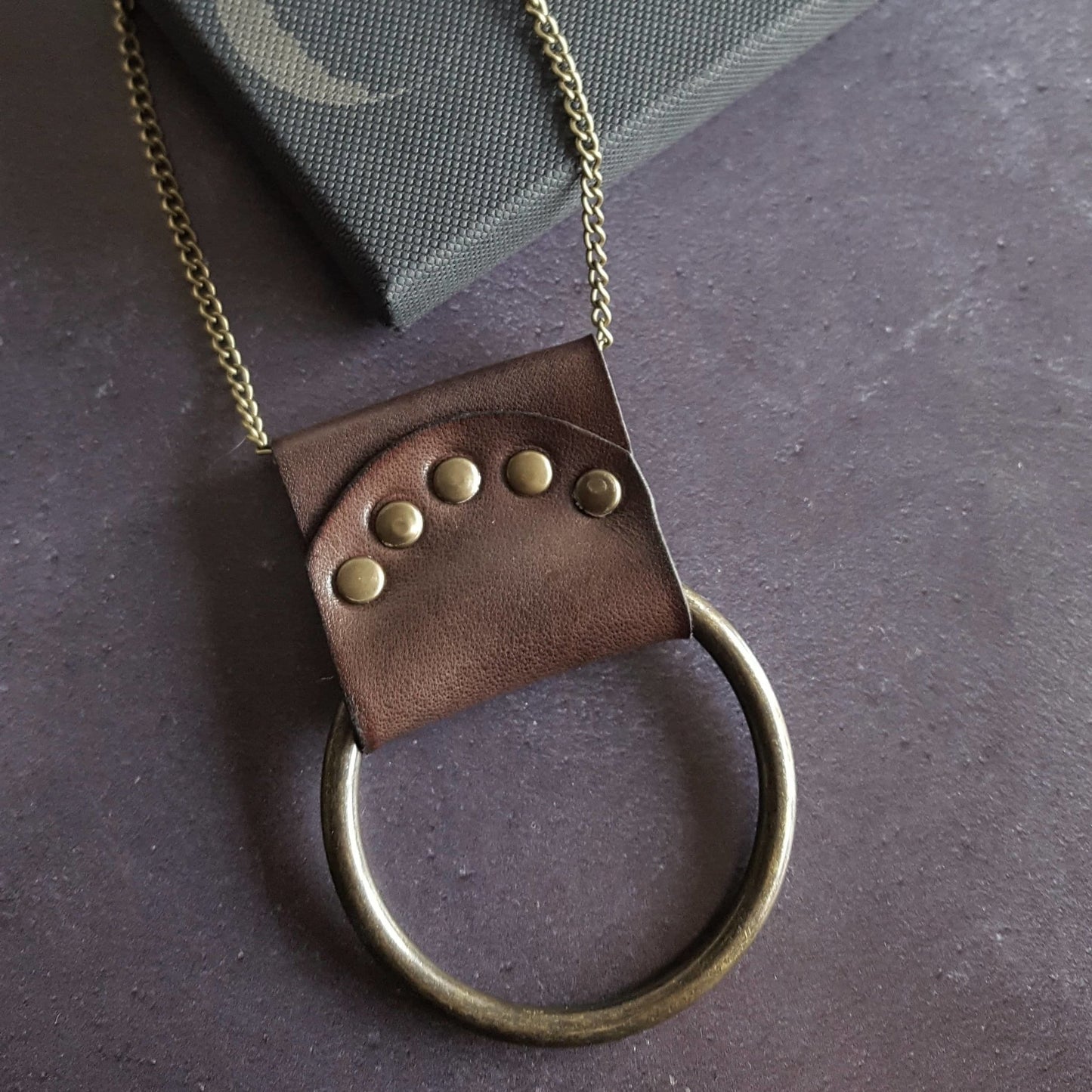 The antique red Lunar Necklace is a beautiful nod to the phases of the moon, hand dyed leather riveted around a solid metal ring lends a little ruggedness to your outfit. A lunar jewelry by Hord.