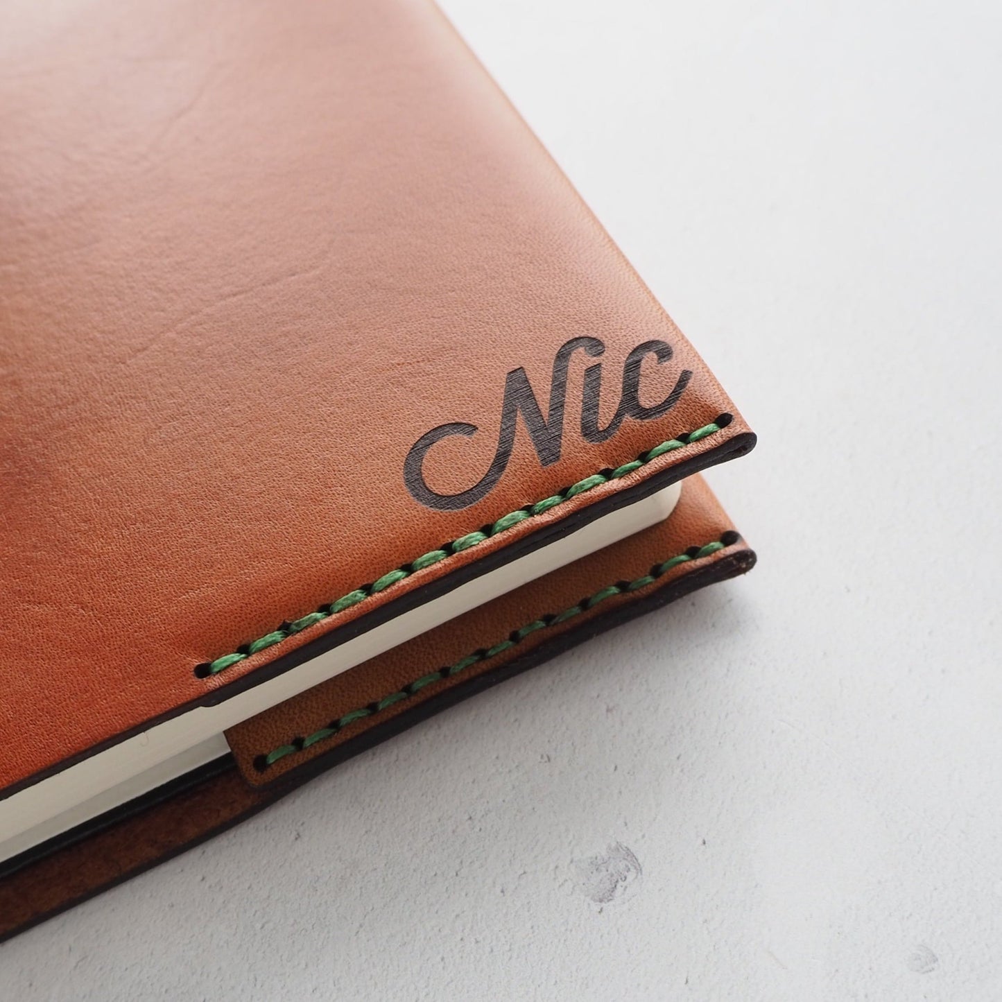 Monogrammed leather notebook cover handstitched with green double-waxed linen thread and personalised with an initial of NIC.