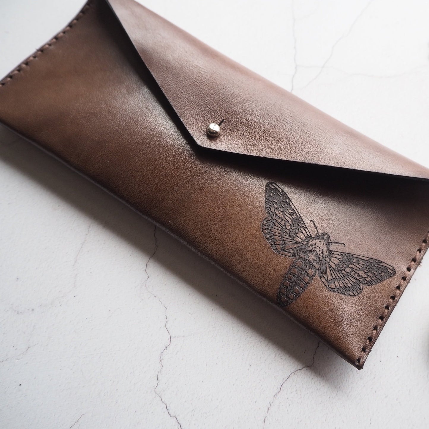 This slim leather pencil case features an engraving of our Moth design.