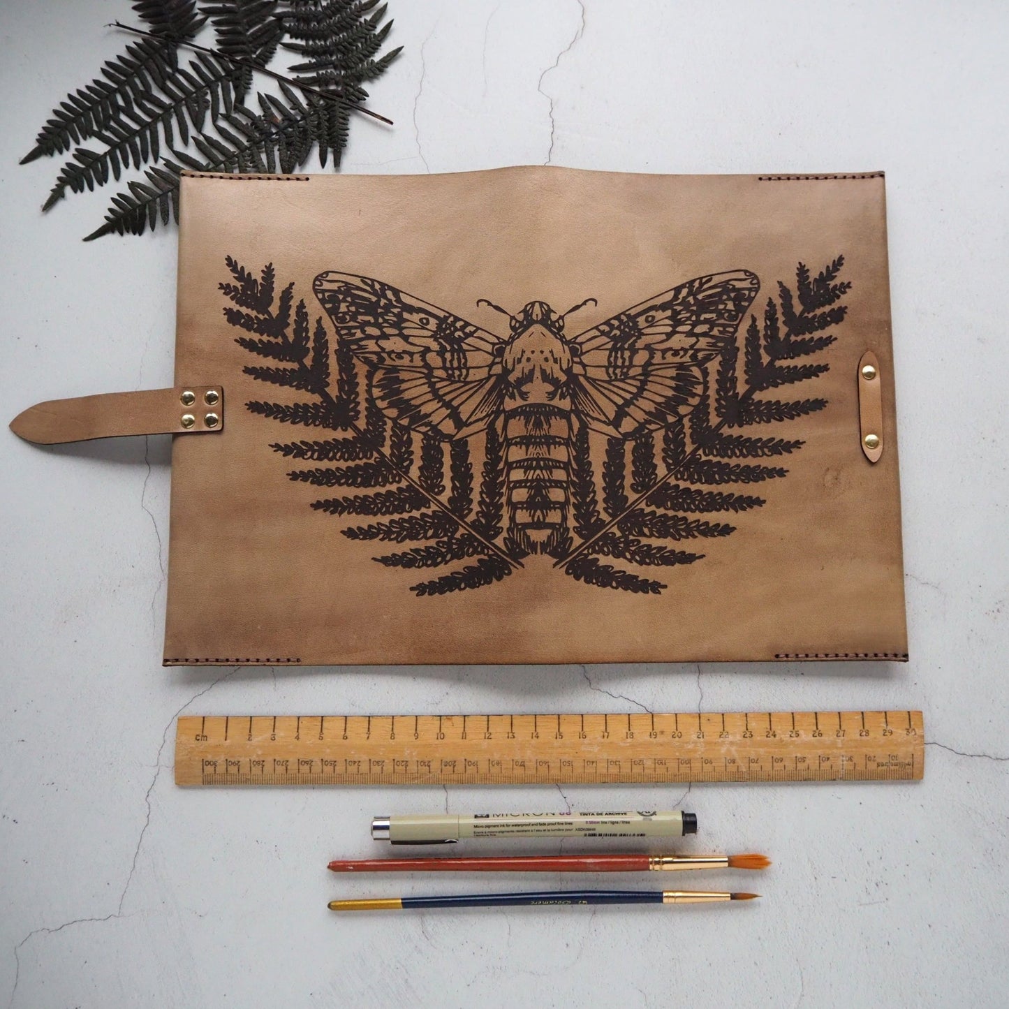 Full view of the Moth Notebook, from the collection of leather covers of journals from HÔRD. This journal cover features HÔRD's moth and fern leaf illustration.