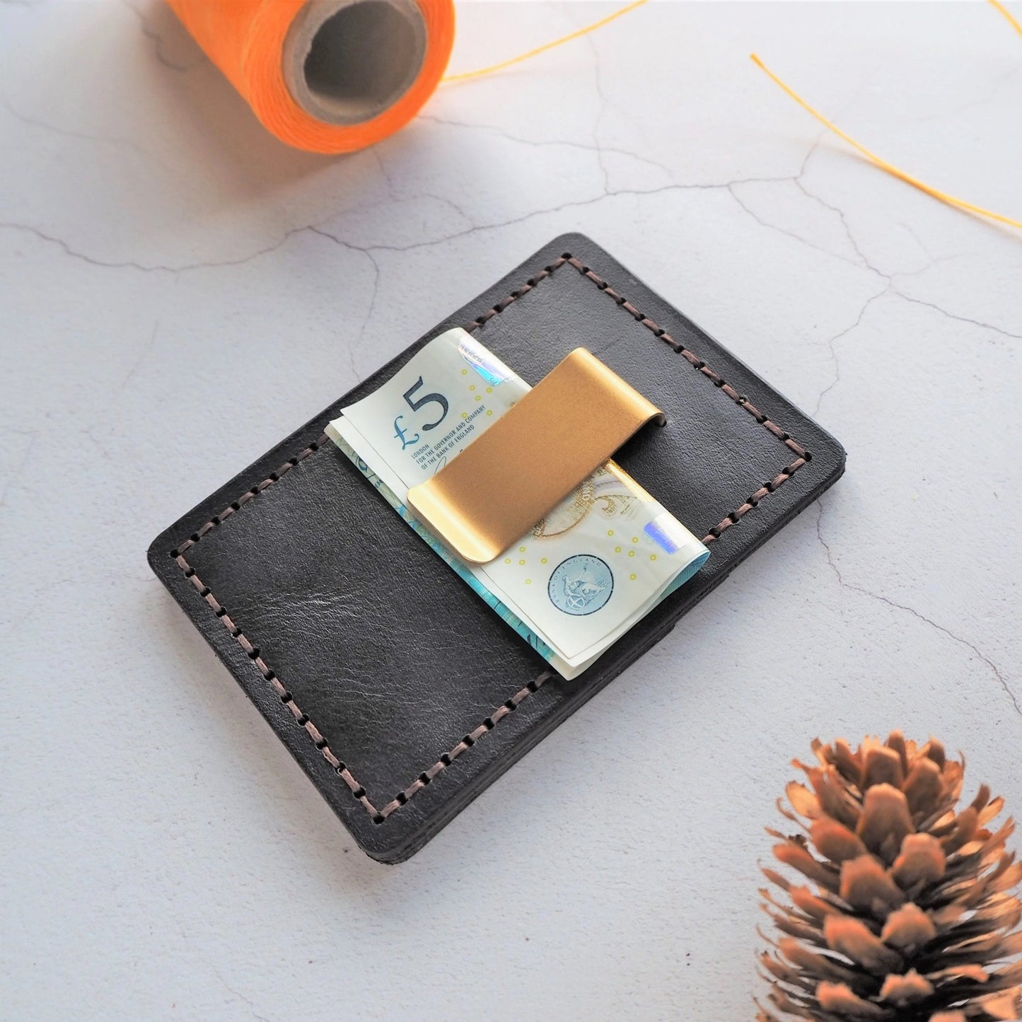 Money folded and being held securely by the money clip of the personalised leather card holder.