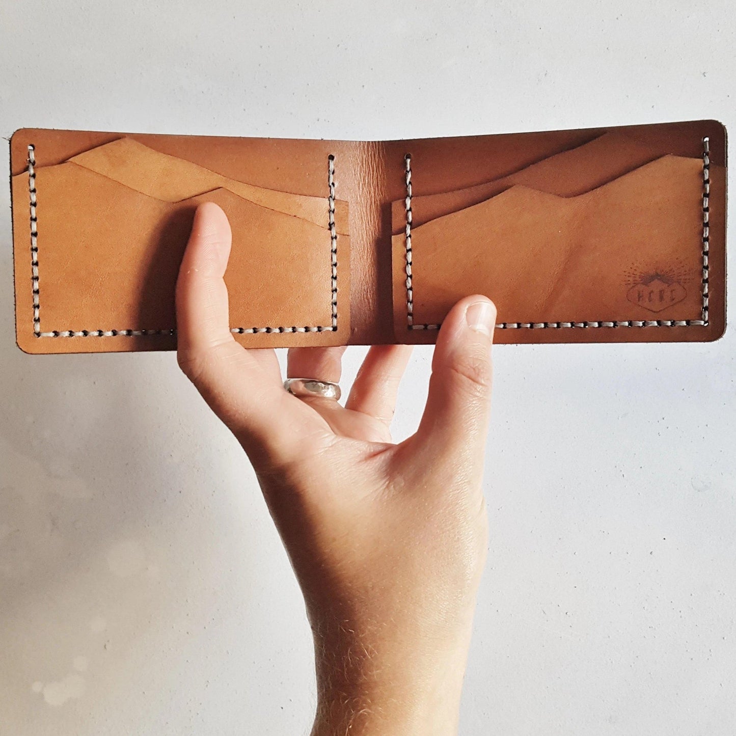 A person holding the engraved leather wallet, the Mountain Wallet, Slimline Bi-Fold by Hord.