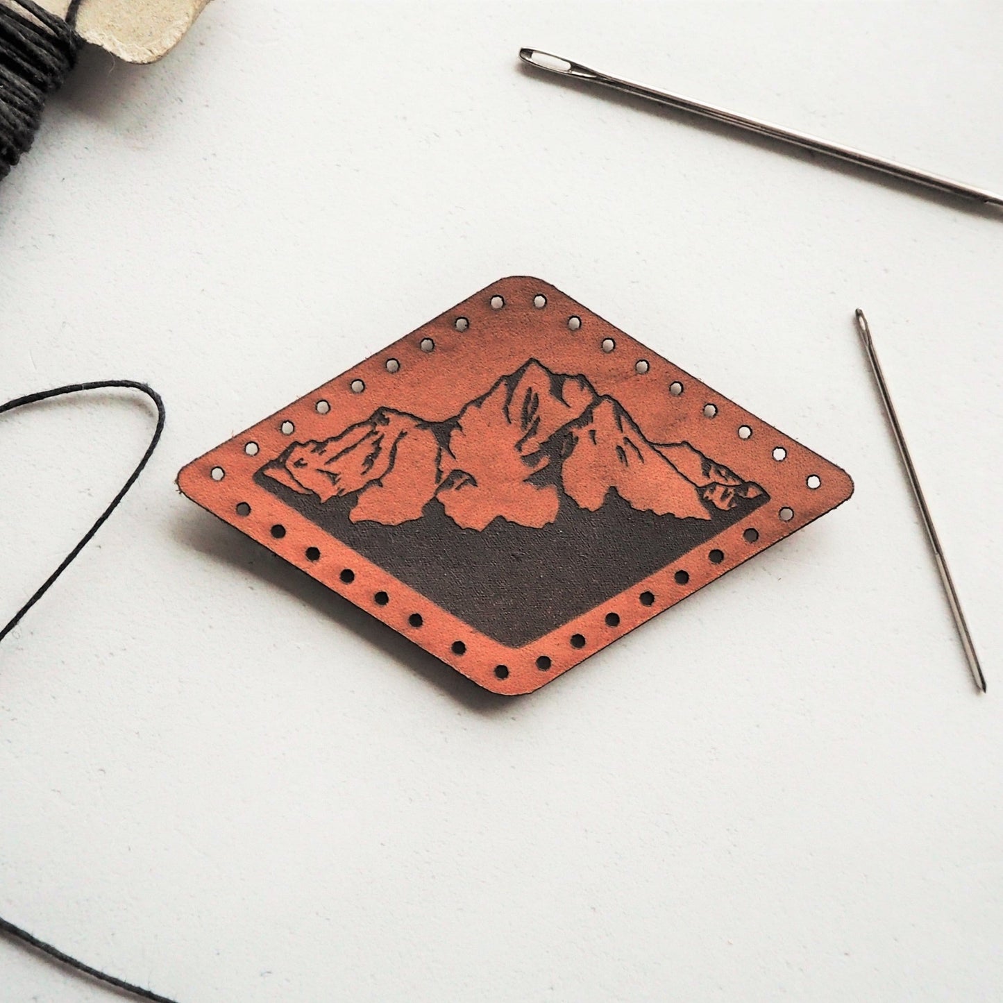 Muntains Leather Patch by HORD - This diamond shaped patch is hand dyed brown and engraved black with one of our mountain illustrations. The perfect gift for lovers of the outdoors, hiking and mountaineering. The mountain patch from Hord.