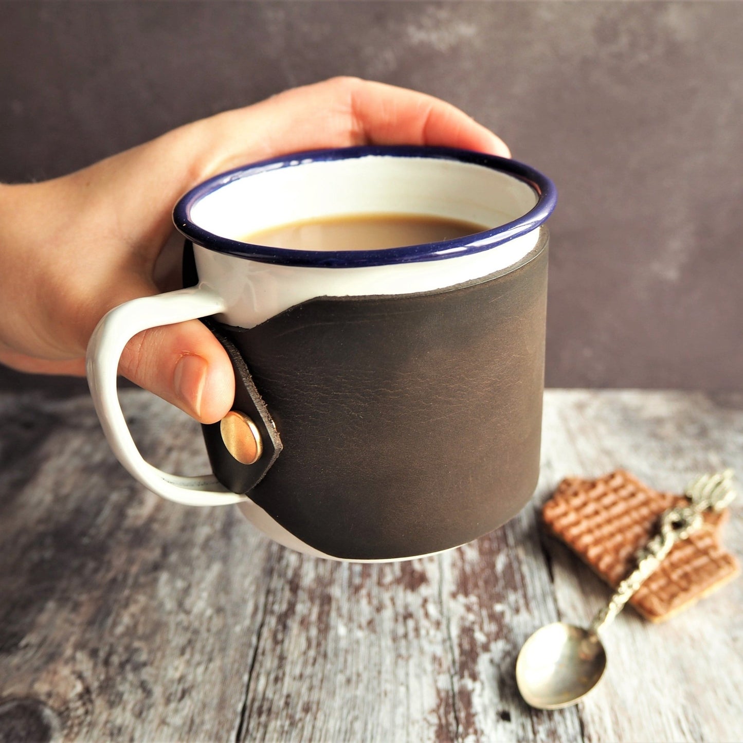Custom enamel mug with leather wrap with hot drink inside. Featured personalised enamel mug is in soft brown leather colour.
