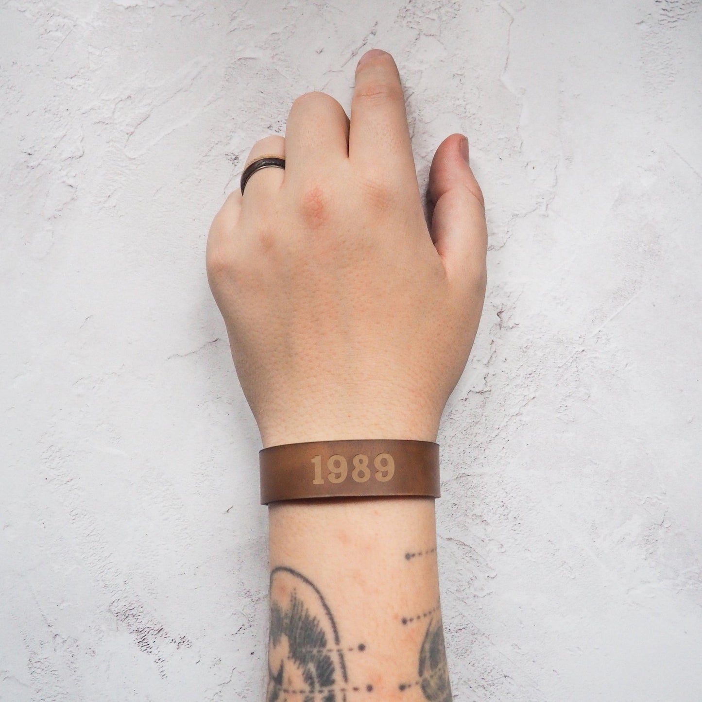 A personalised leather bracelet from Hôrd featuring a custom year. The cuff is engraved with the year 1989 in a chunky font style.