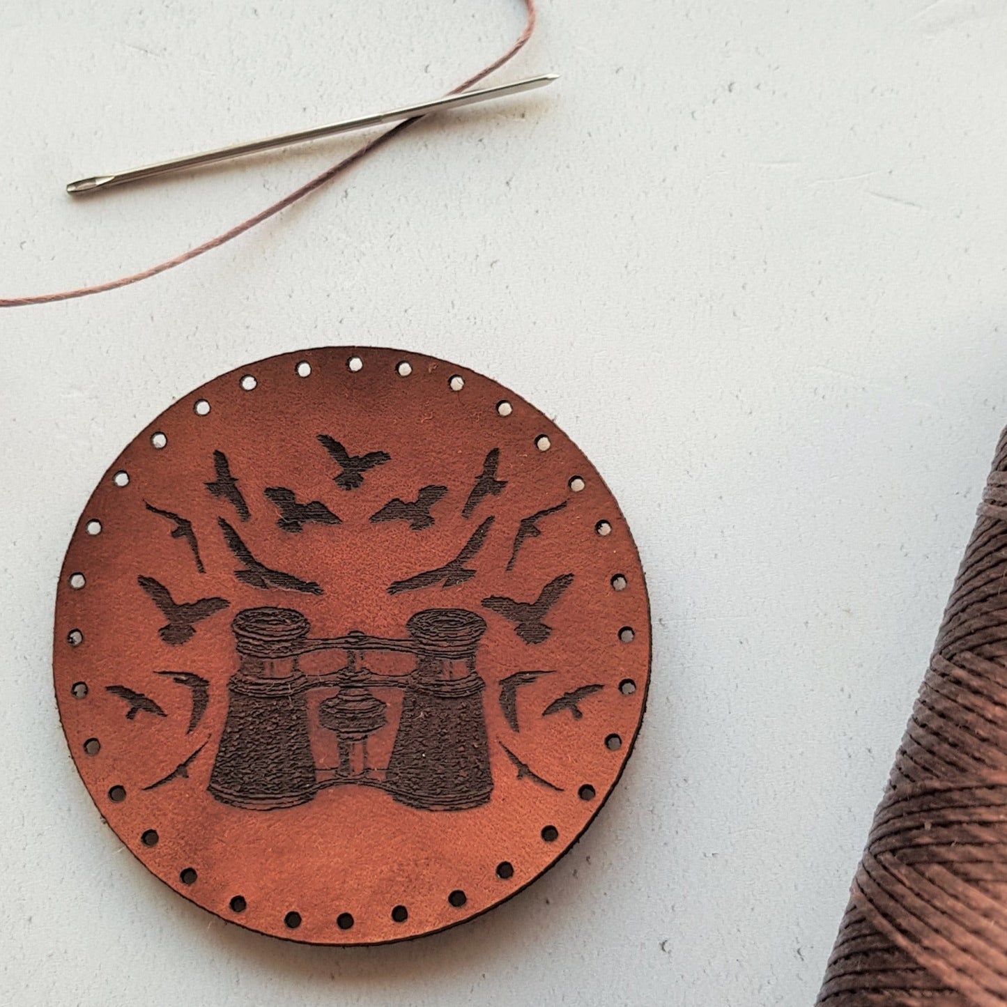 The bird watching leather patch is a circular brown piece which features a pair of vintage binoculars surrounded by a plethora of bird silhouettes, a perfect gift for those that love to keep an eye on nature and particularly our feathered friends. The Birding Patch from Hord.