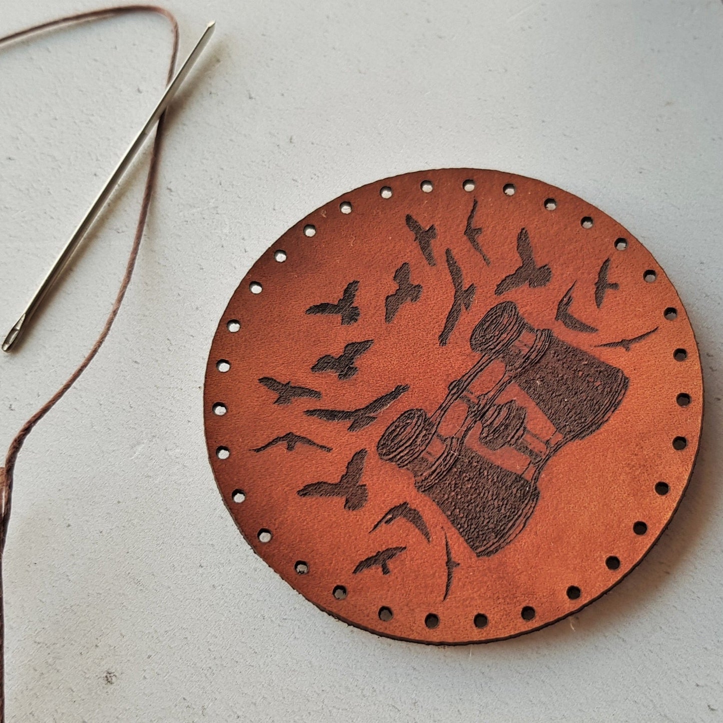 A close up of HORDs birdwatching patch, showing the texture of the grain of the leather and the depth of the textural and tactile black engraving. The Birding Patch from Hord.