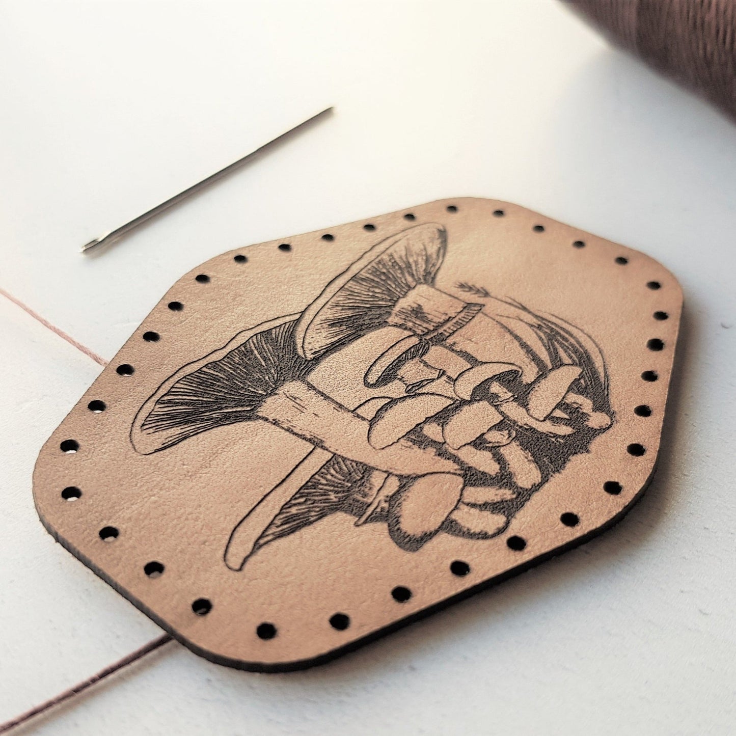 A unique illustrated patch engraved with beautiful wild mushrooms. this close up image shows the lovely texture of the engraving. The forager patch from Hord.