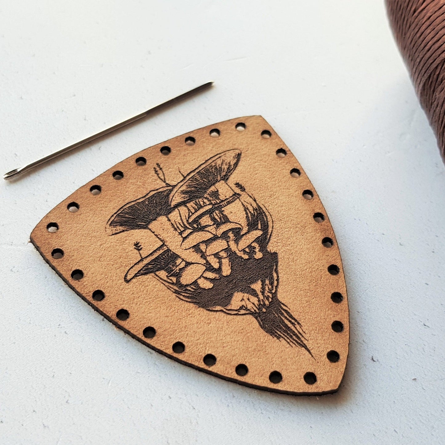 Chunky mushrooms have been hand illustrated and engraved onto this amazing leather patch. This close up photo shows the tactile and textural quality of the engraving. The mushroom patch from Hord.