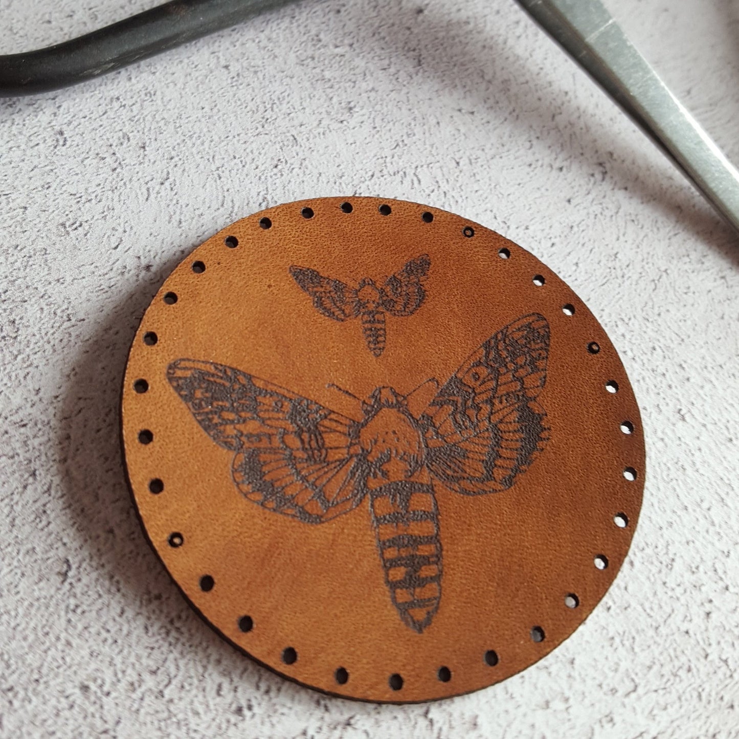 A close up of the handmade moth patch from HORDs entomology collection of insect themed leather patches. The Moth Patch from Hord.
