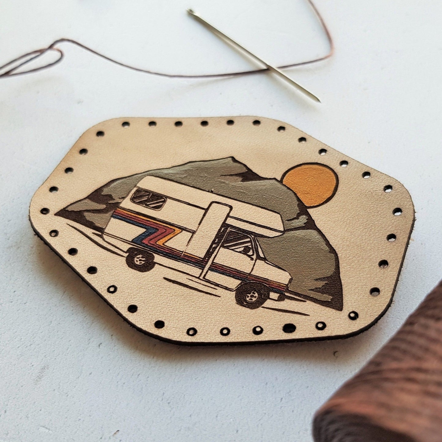A close up of the HORD Motorhome (caravan) patch on textural natural leather. Engraved and hand painted with a totally 80s road trip vibe