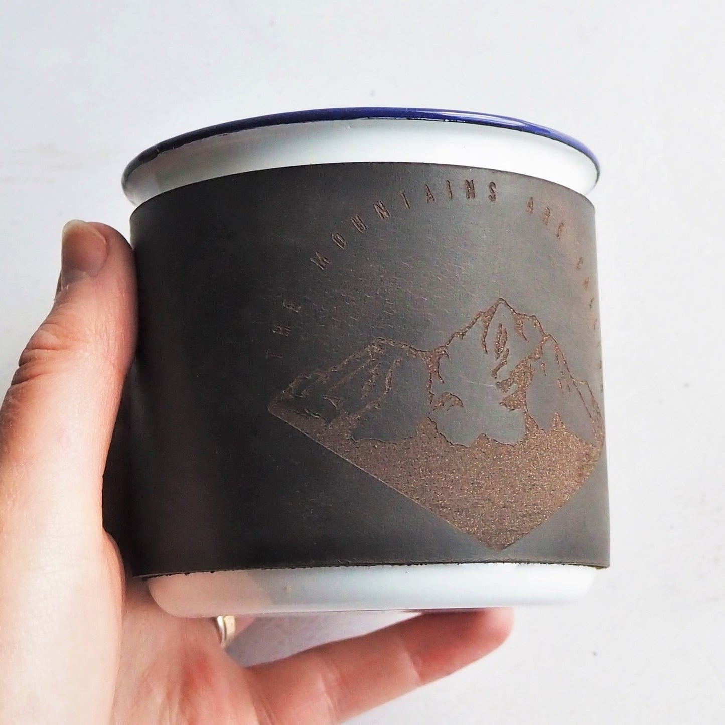 The Mountains are Calling Enamel Mug, a leather wrapped camping enamel mug from HÔRD.