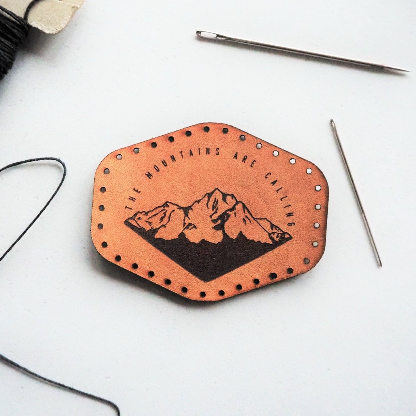 The Mountains Are Calling, Leather mountain Patch by HORD - This leather patch is hand dyed and engraved with wonderful mountains and the quote 'The Mountains Are Calling'. Perfect stocking fillers or gifts for lovers of the outdoors, mountaineering and hiking.
