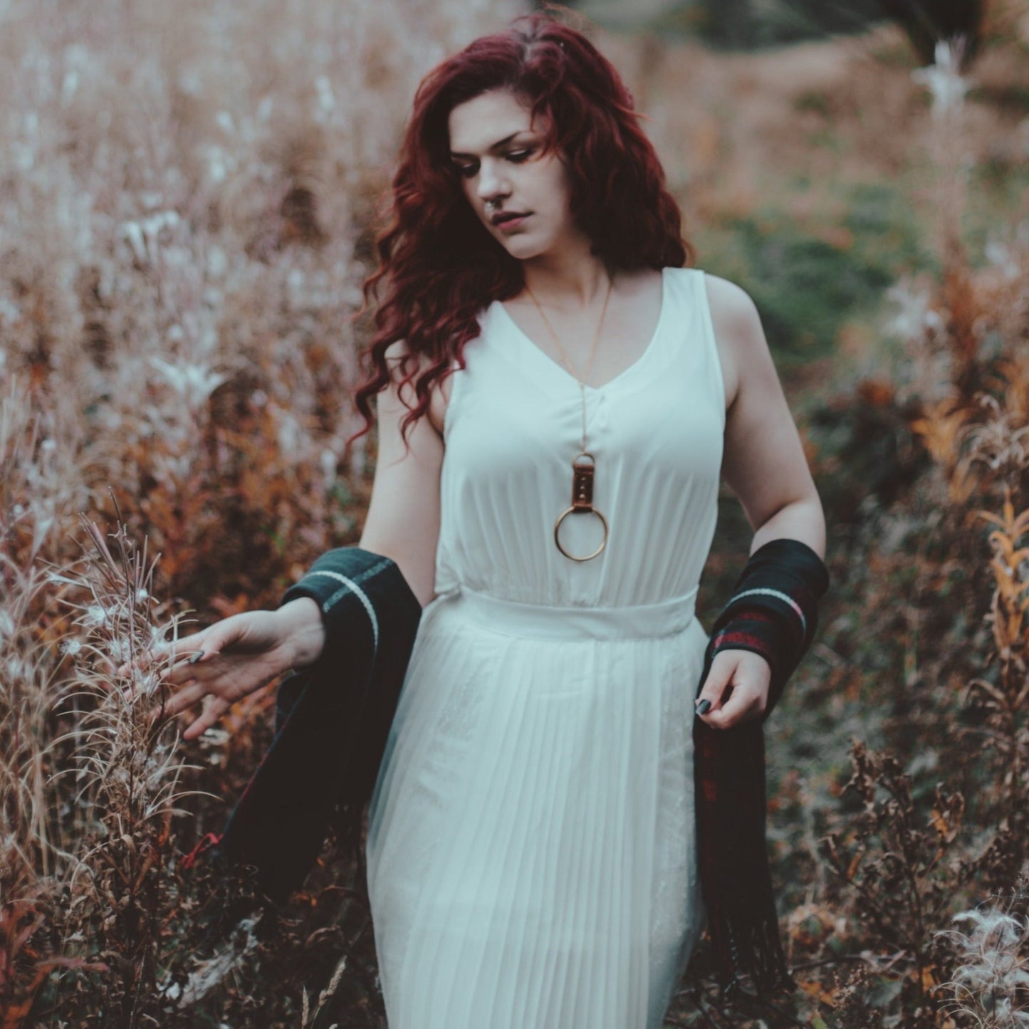 A person styling their outfit with the solar necklace from Hord.