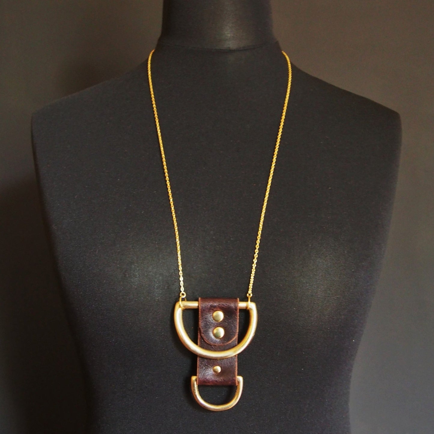 The Wane Necklace is inspired by the phases of the moon. Soft brown leather is riveted around two solid brass d-rings, chunky and rugged. A leather necklace by Hord.