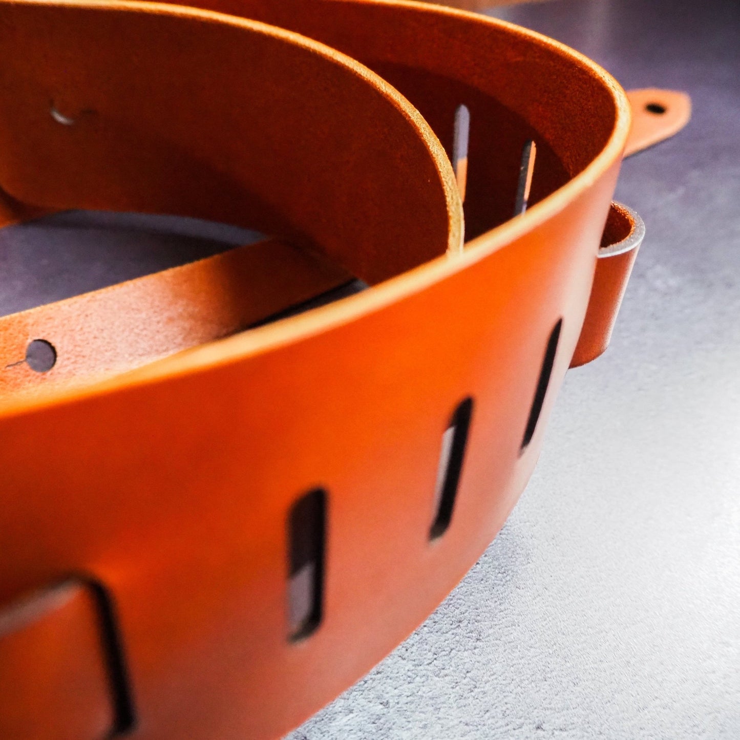 Adjustable holes present on the thick leather guitar strap.