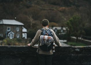  A man stood on a bridge in Wales wearing a HORD beanie and carrying a HORD blanket and adventure bottle.
