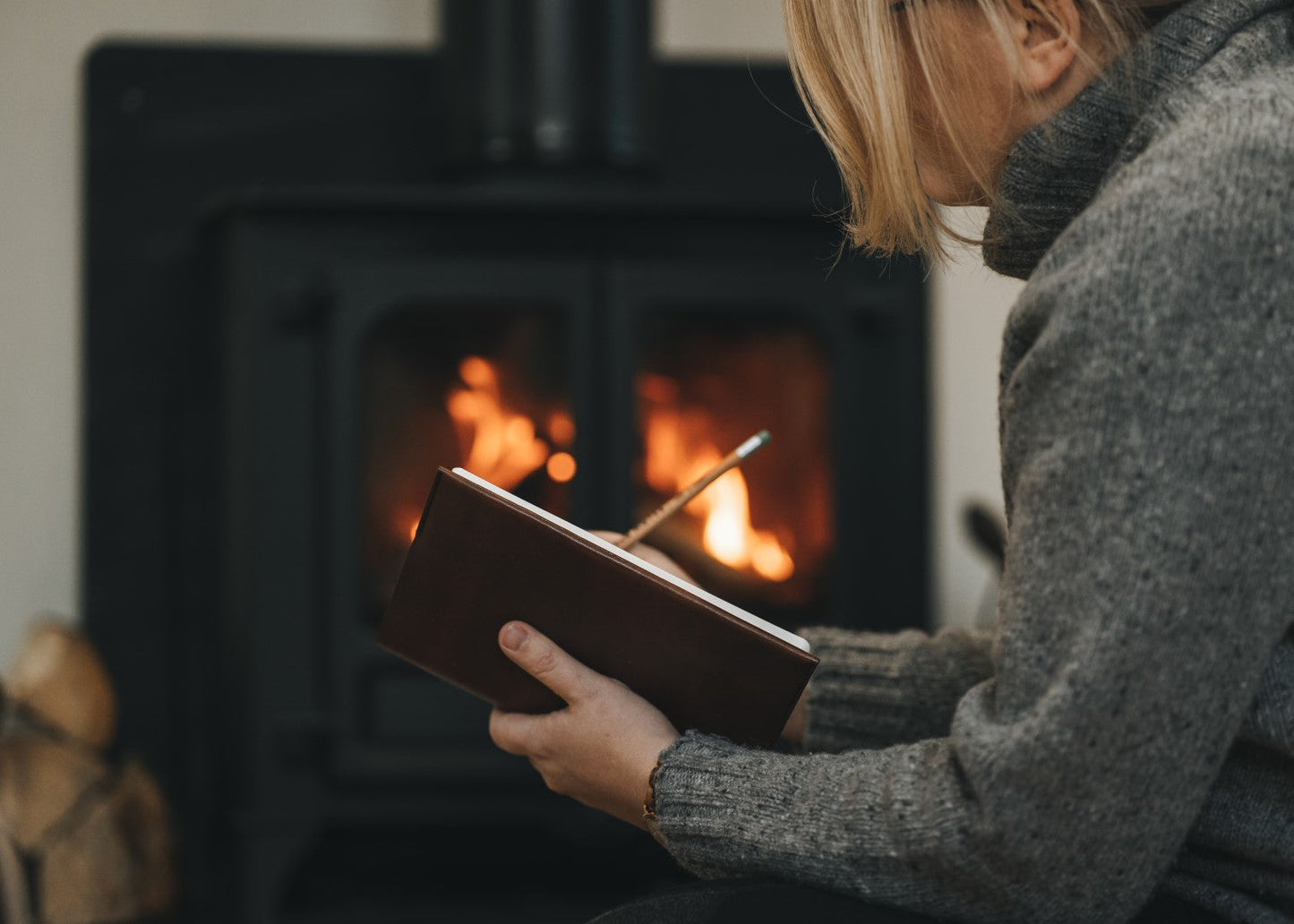 a woman sits by a stove writing in her journal