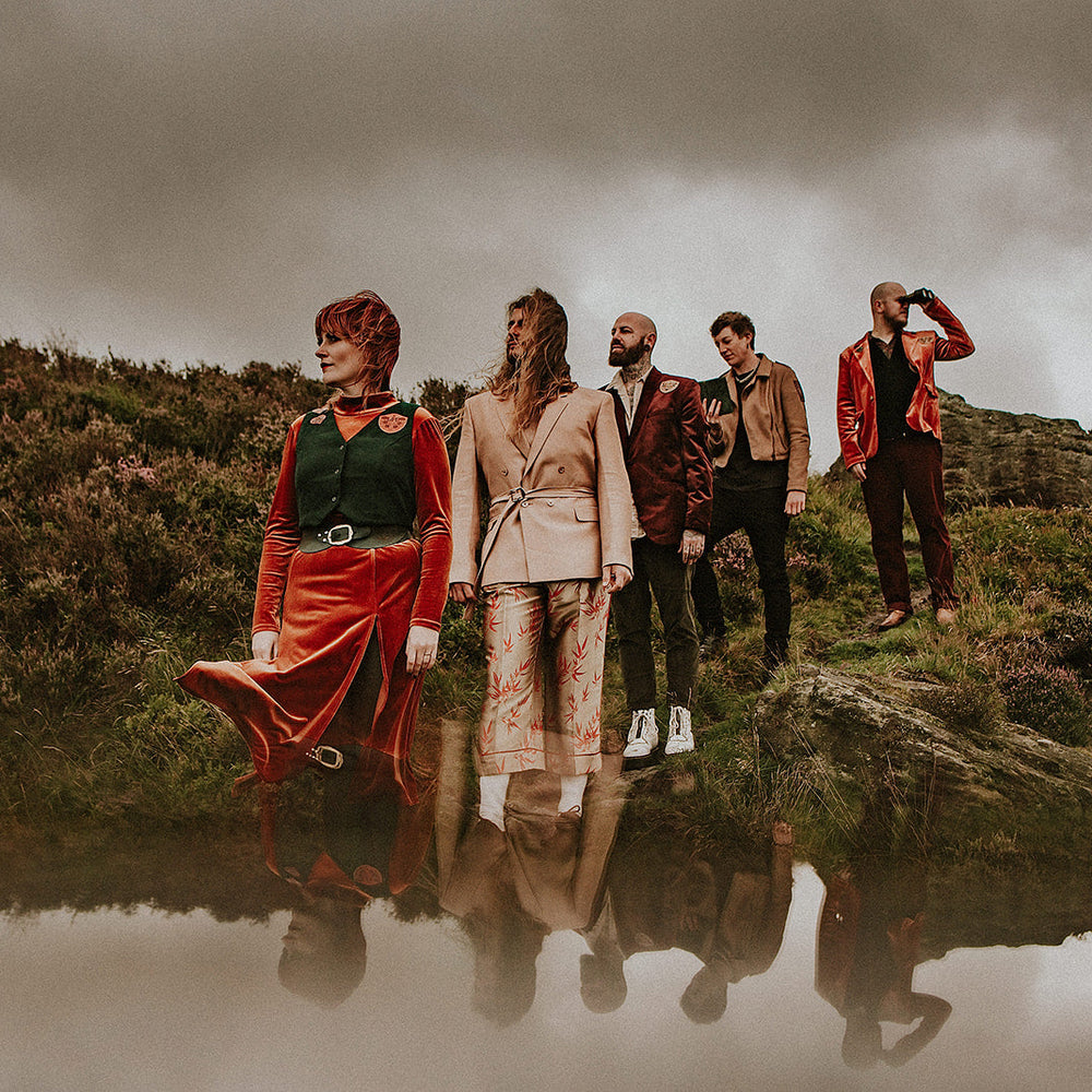 five people stood on the Yorkshire moors of marsden wearing orange and green psychedelic accessories made from leather. The photograph has multiple exposure, reflecting the sky at the bottom