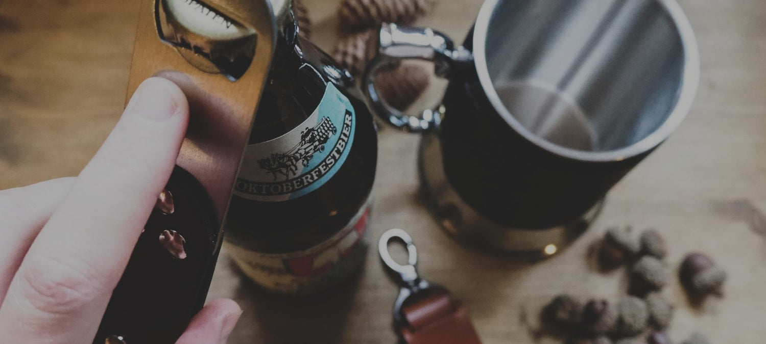 A bottle opener being used on an oktoberfest beer, next to a leather tankard