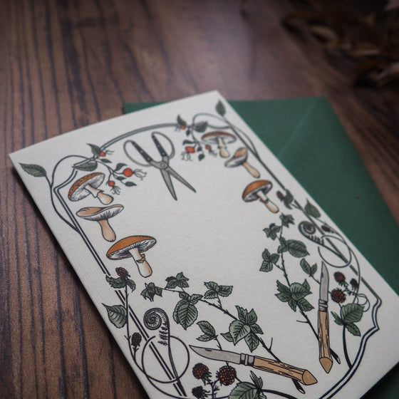 Forager Greeting Card - A vibrant illustration of foraging tools surrounded by mushrooms, blackberries, and rosehips