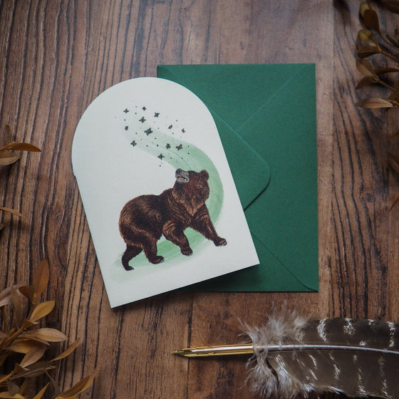 Charming bear chasing butterflies on a beautifully illustrated greeting card.