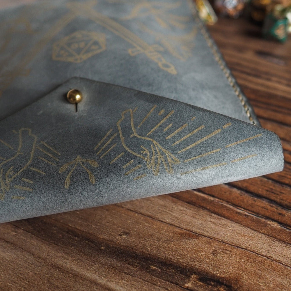 
                  
                    Gray leather pouch with gold engraved designs on a wooden surface
                  
                