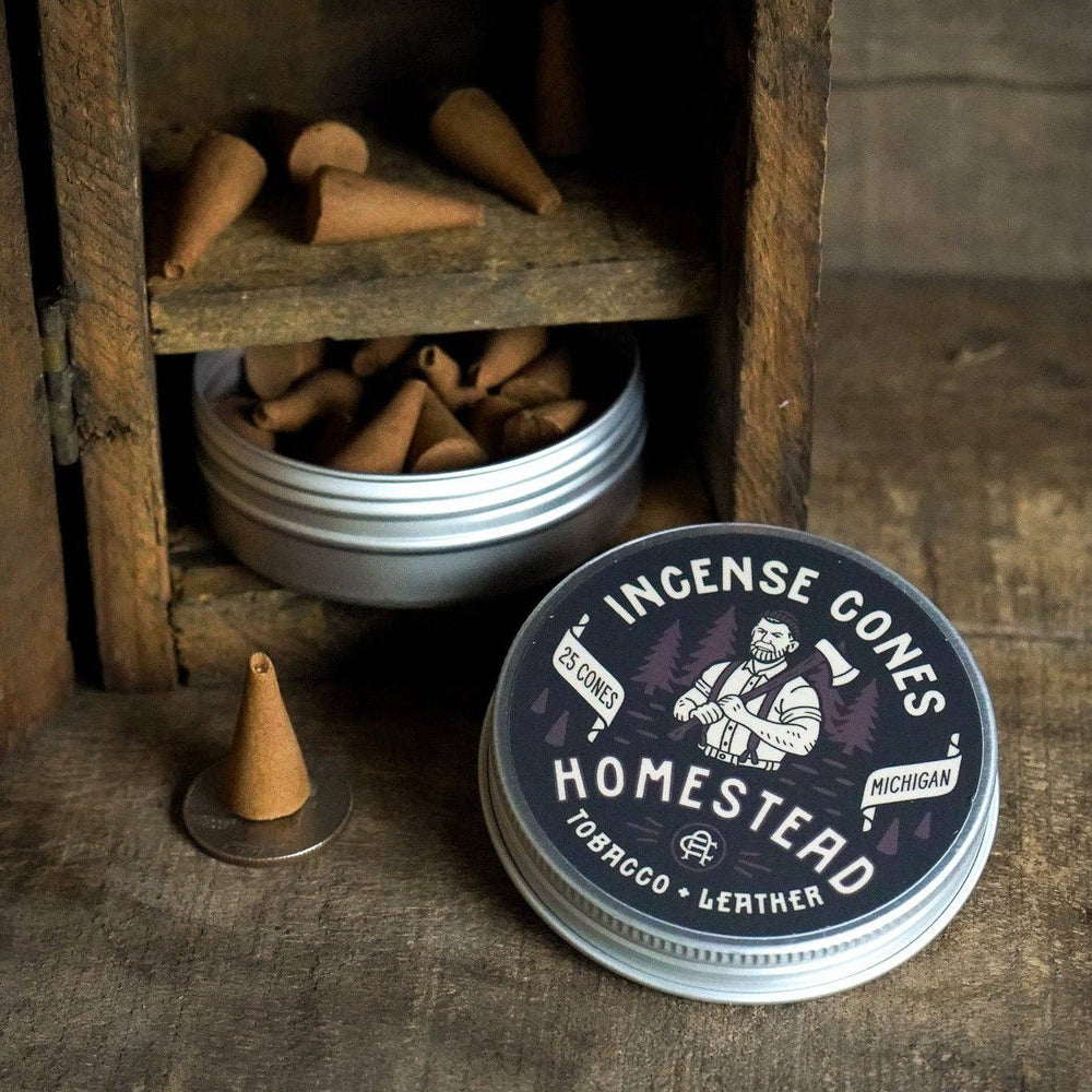 Incense cones in a wooden holder with a 'Homestead' incense container on a rustic wooden surface.