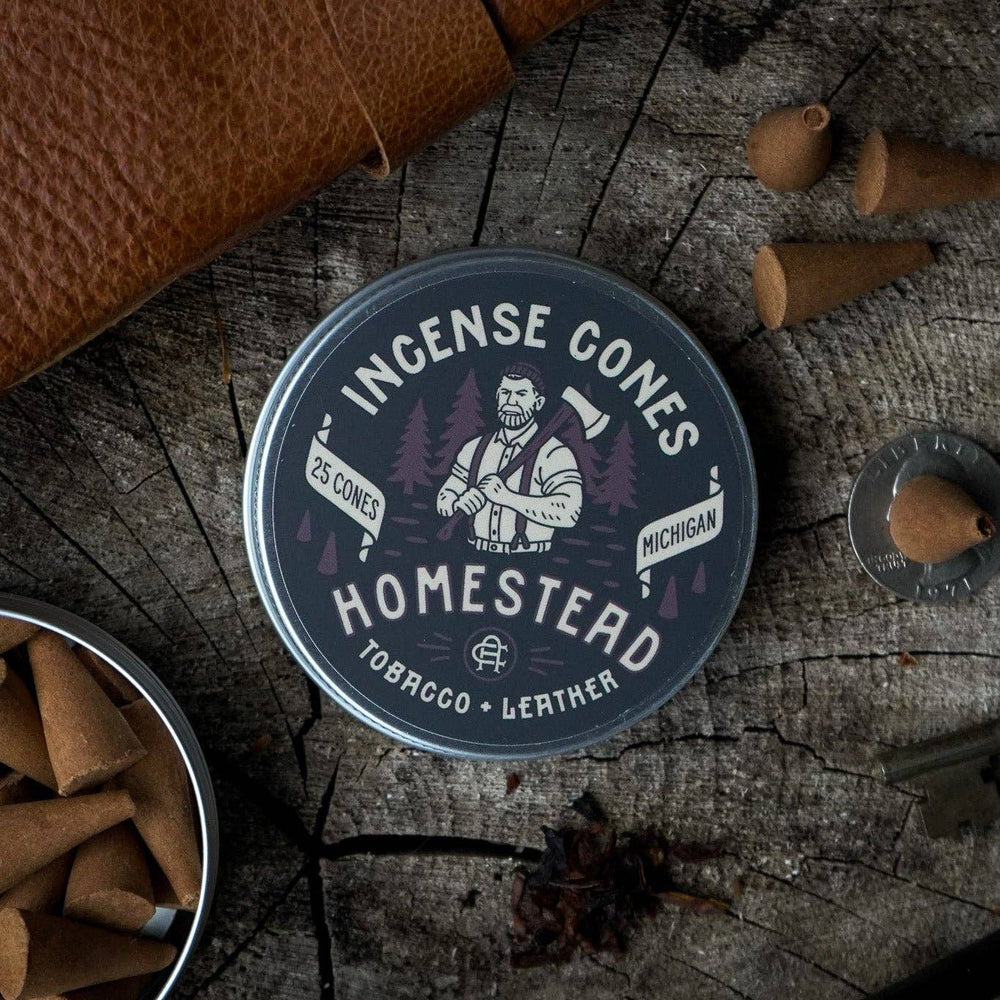 Homestead Incense product on a rustic wooden surface with a pipe and cones.