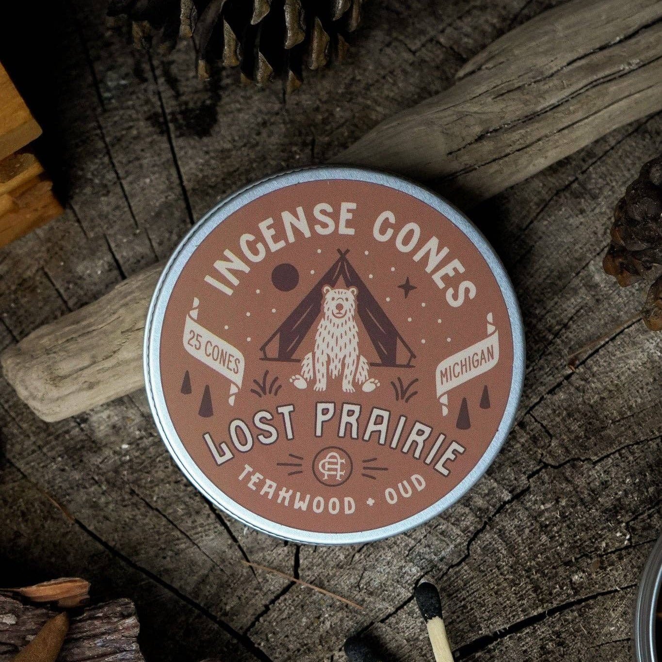 Incense cones container with 'Lost Prairie' branding on a wooden surface with matches and pinecones.