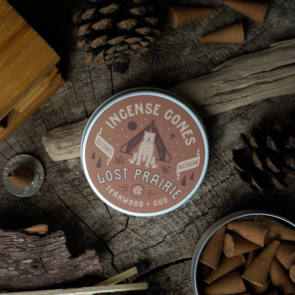 
                  
                    Lost Prairie incense cones packaging on a wooden surface with incense cones and sticks.
                  
                