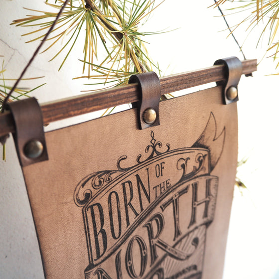 Closer look at the Born of the North banner, engraved with the text; this leather decoration is available in 2 different sizes. A leather decoration by Hord.