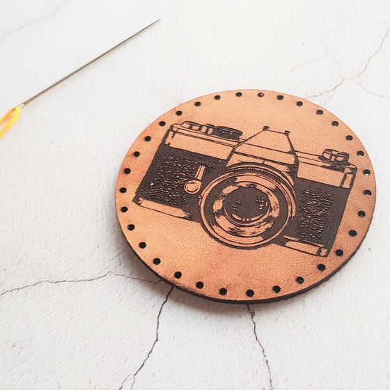 The HORD Camera Patch is shown at an angle catching the light and demonstrating the depth of the engrave in the surface of the leather, making for a nice textural piece of wearable art. A photographer patch from Hord.