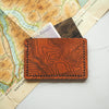 The engraved leather card holder with custom topography with cash and cards stored safely. 