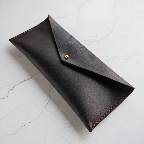 The Dark Leather Pencil Case that has been fastened with a stud.