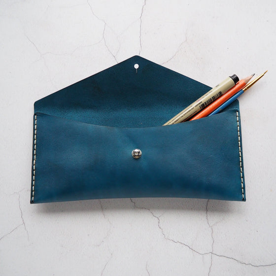 The Dyed Leather Pencil Case with a pen, pencil, and brush stored inside.