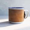 A camping enamel mug from HÔRD with soft sand leather colour.