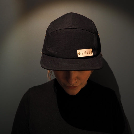 The black camper cap worn by an individual, by Hord.
