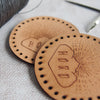 A pair of our HORD logo leather patches showing the texture of the leather grain and a slight patina
