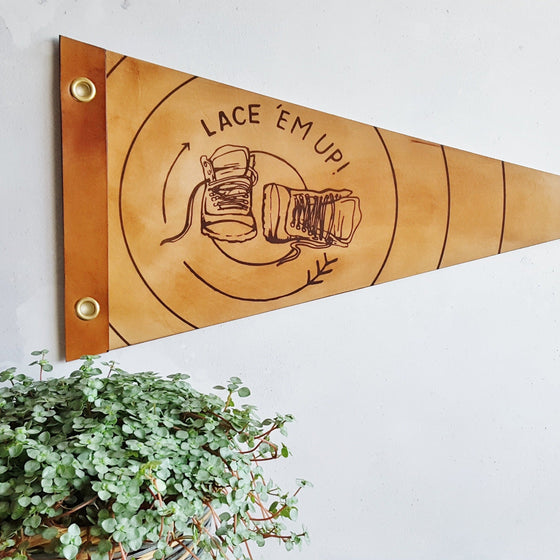 A closer view of the 'lace 'em up' leather pennant, a camping home decor by Hord - The perfect gift for walkers and hikers to display on their wall.